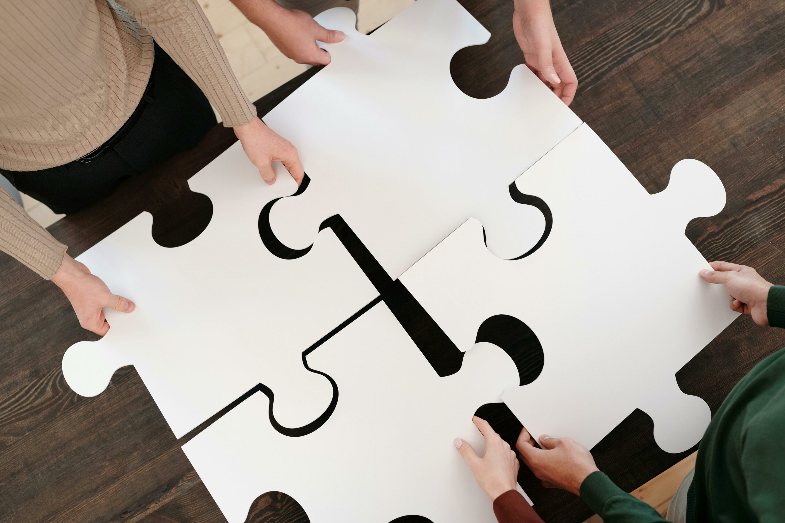 Group collaborating on assembling large puzzle pieces symbolizing teamwork and unity.