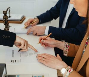 Hands signing a divorce decree, with a justice statue nearby, symbolizing legal proceedings.